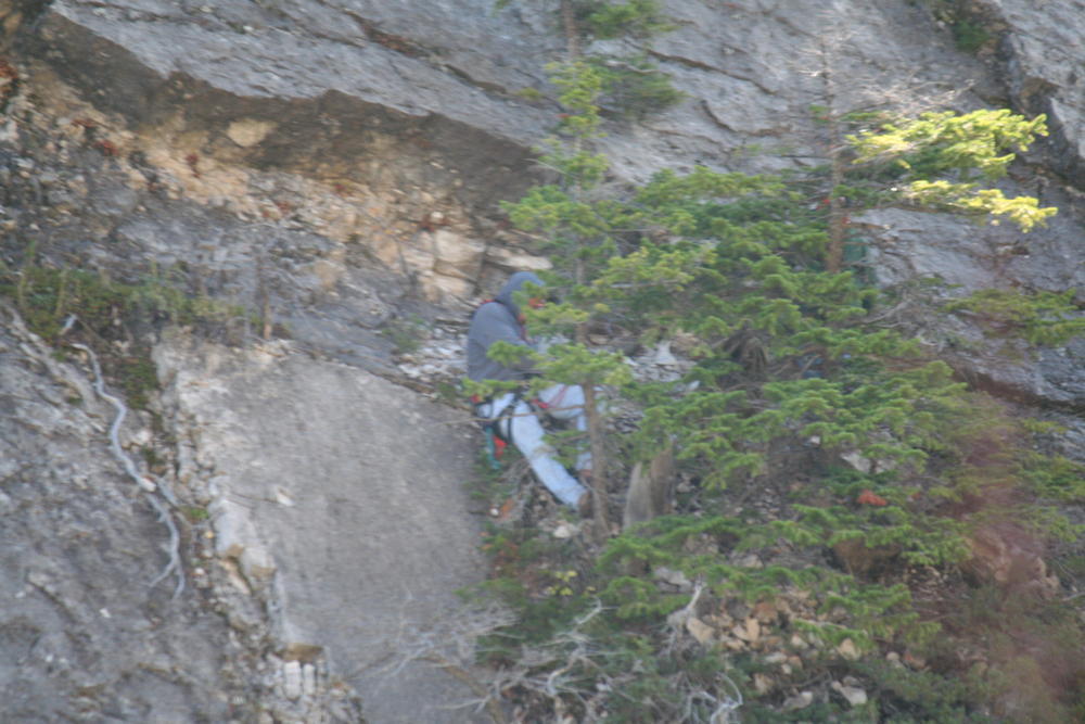 person repelling down the side of a rocky cliff