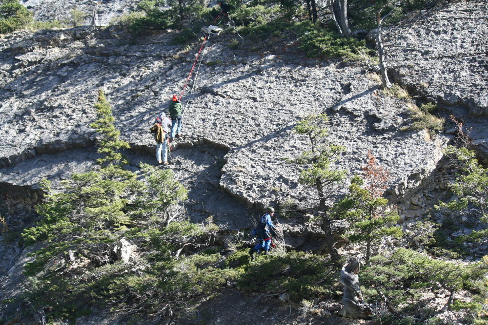 3 people repelling down the side of rocks