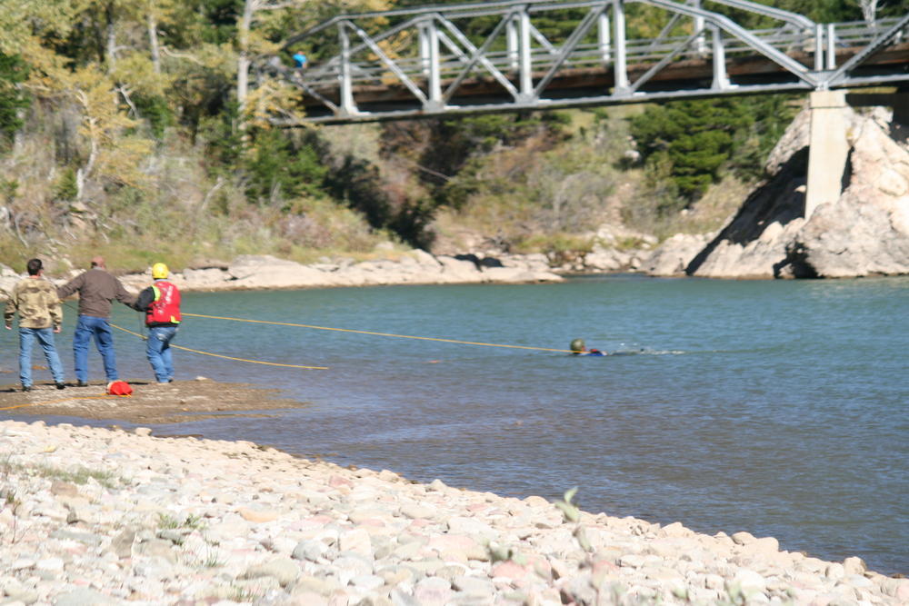 3 people pulling someone out of the water with ropes